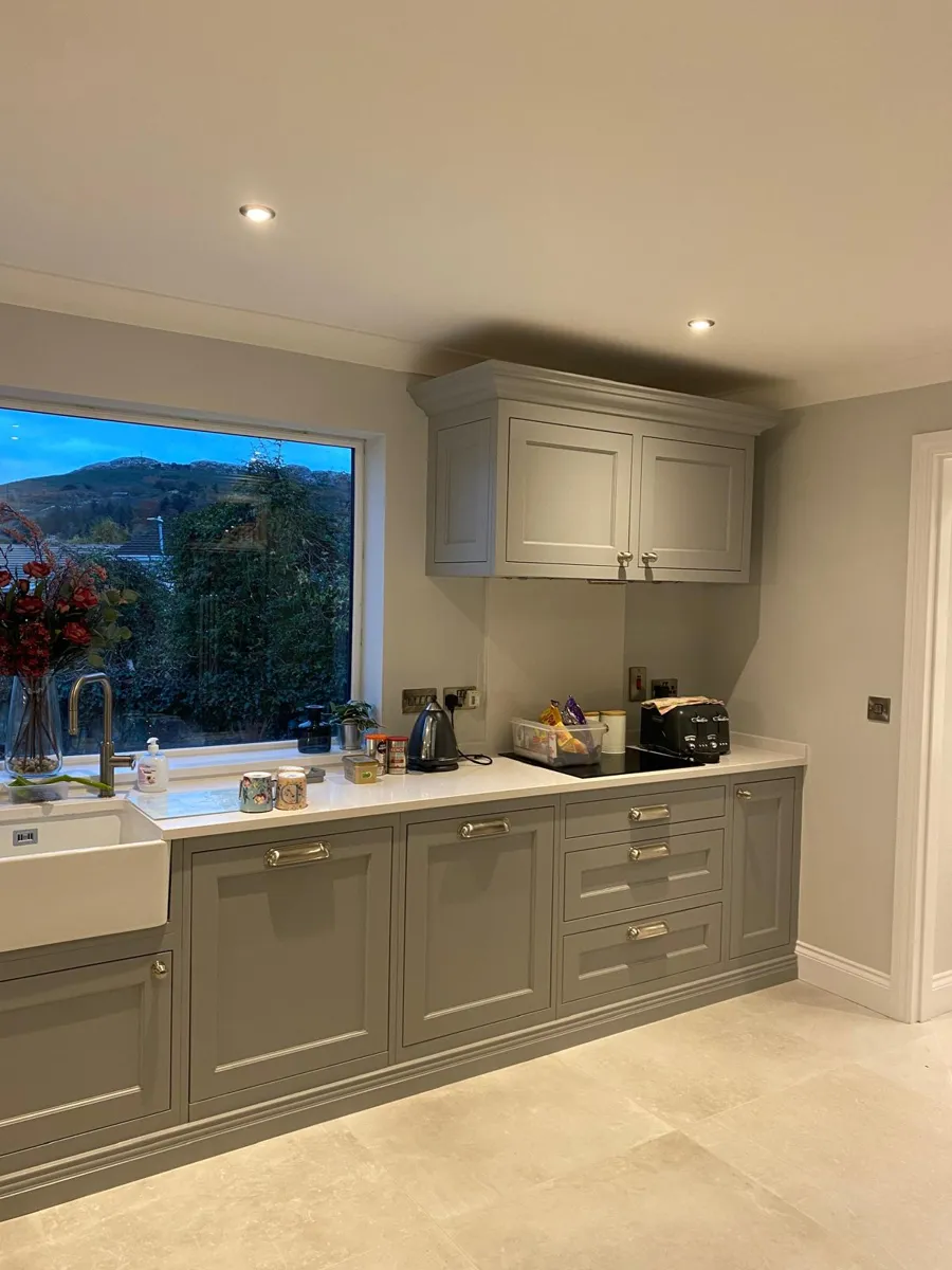Kitchen cabinets painted soft grey under a big window