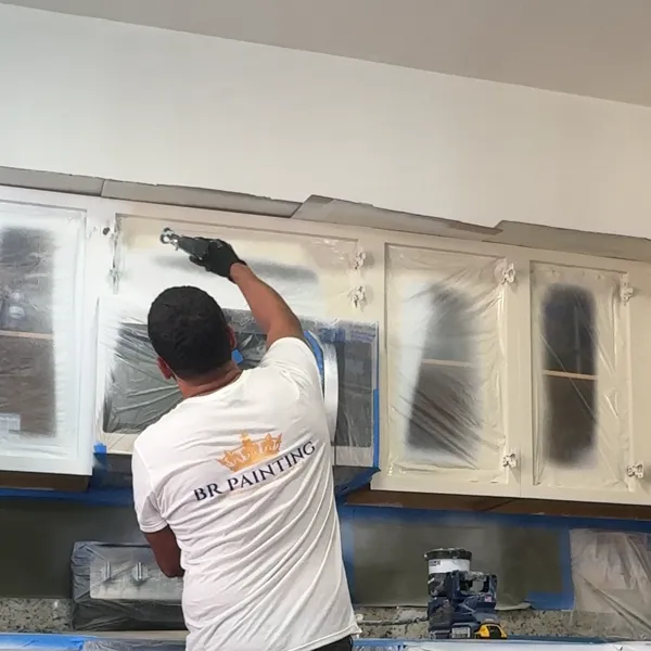 Leandro spraying the cabinet boxes in a fully covered kitchen