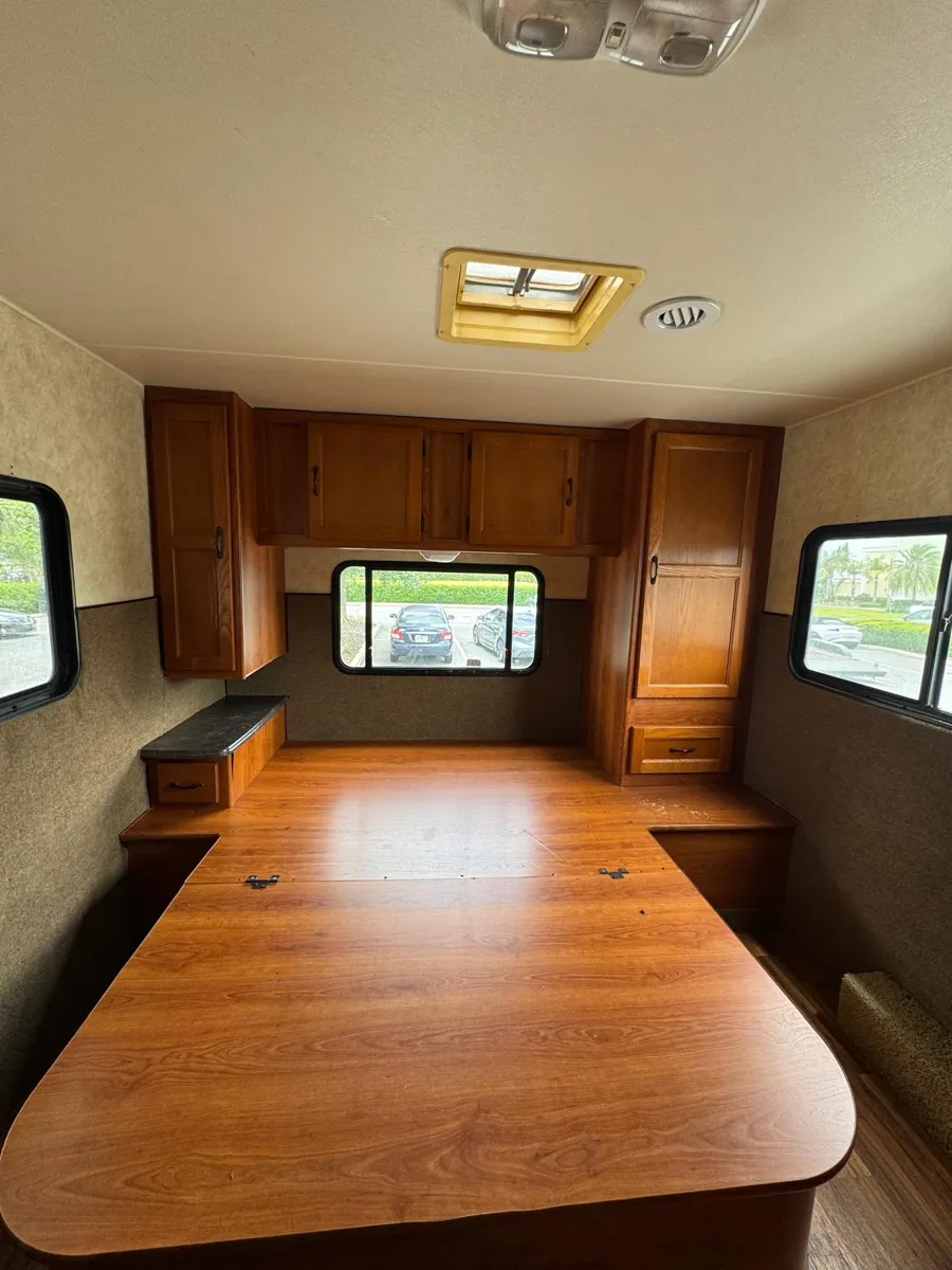 Back of the motorhome with wood cabinets and a wood table before painting